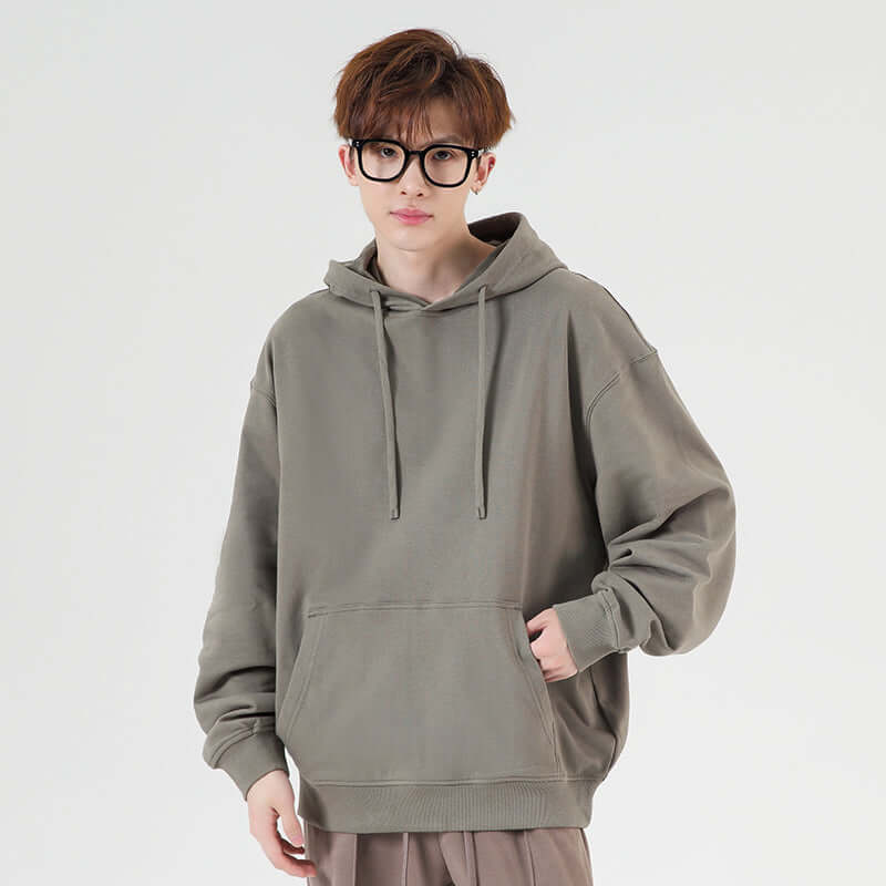 Blank Oversized Hoodie in olive green worn by a model, featuring a relaxed fit, drawstring, and front pocket.