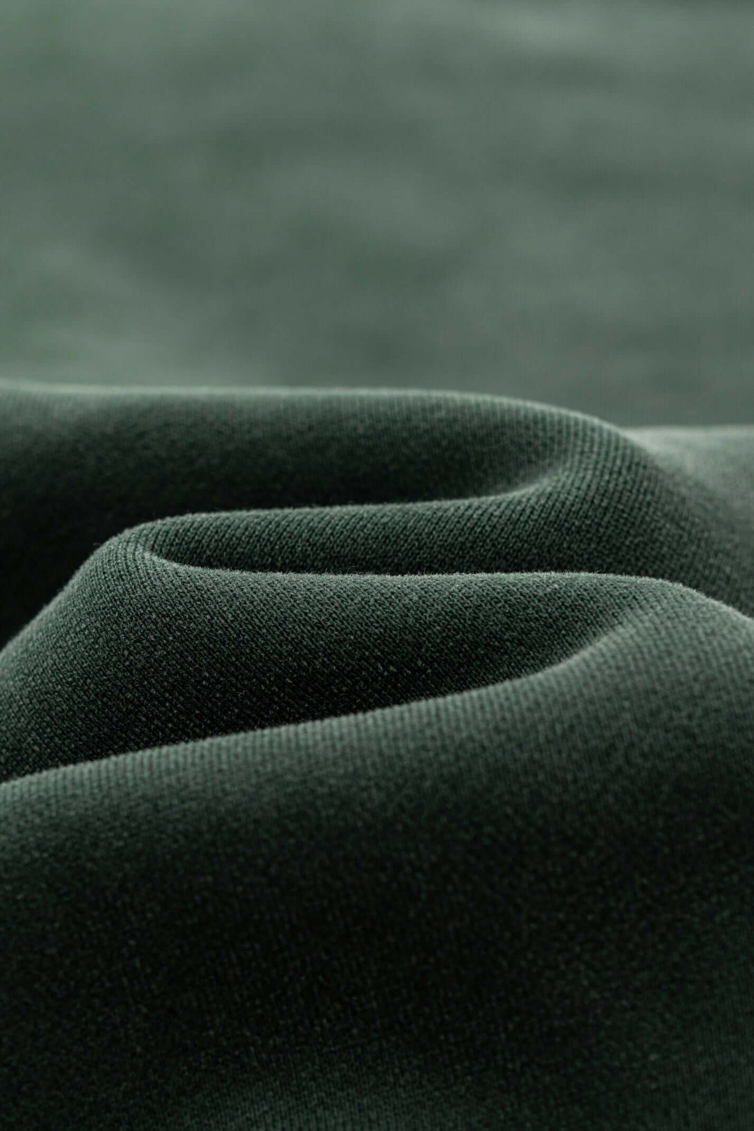 Close-up of soft, textured green fabric showcasing the quality of the Distressed Panel Crewneck.