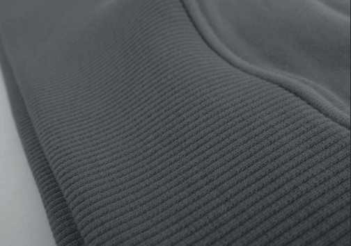 Detail shot of the 1x1 ribbed hem for a secure fit on the unisex hoodie.