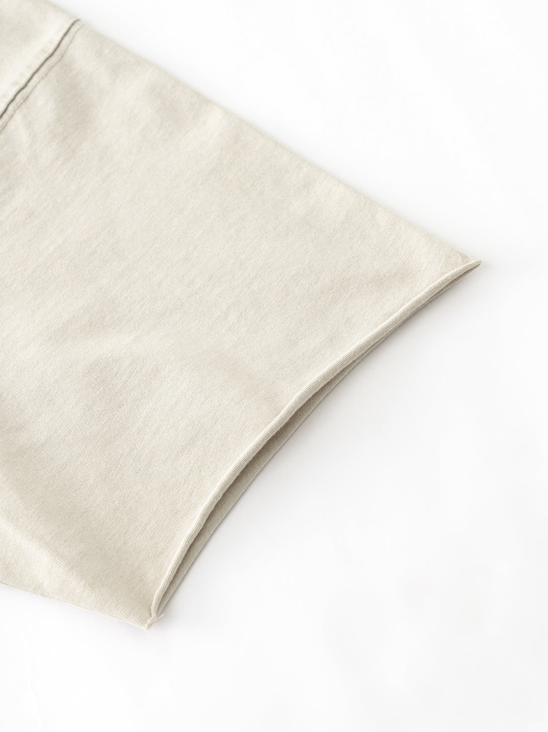 Distressed sleeve trim detailing on Apricot pigment-dye cotton tee, production finishing sample.