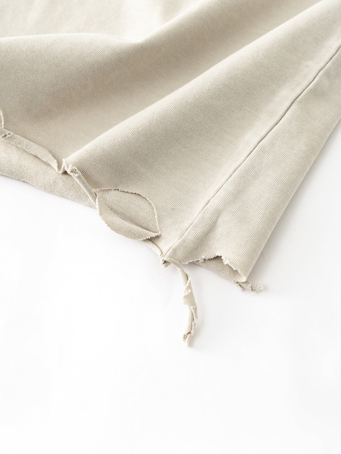 Raw-edge hem finishing with distressed texture on Apricot oversized tee, bulk production consistency.