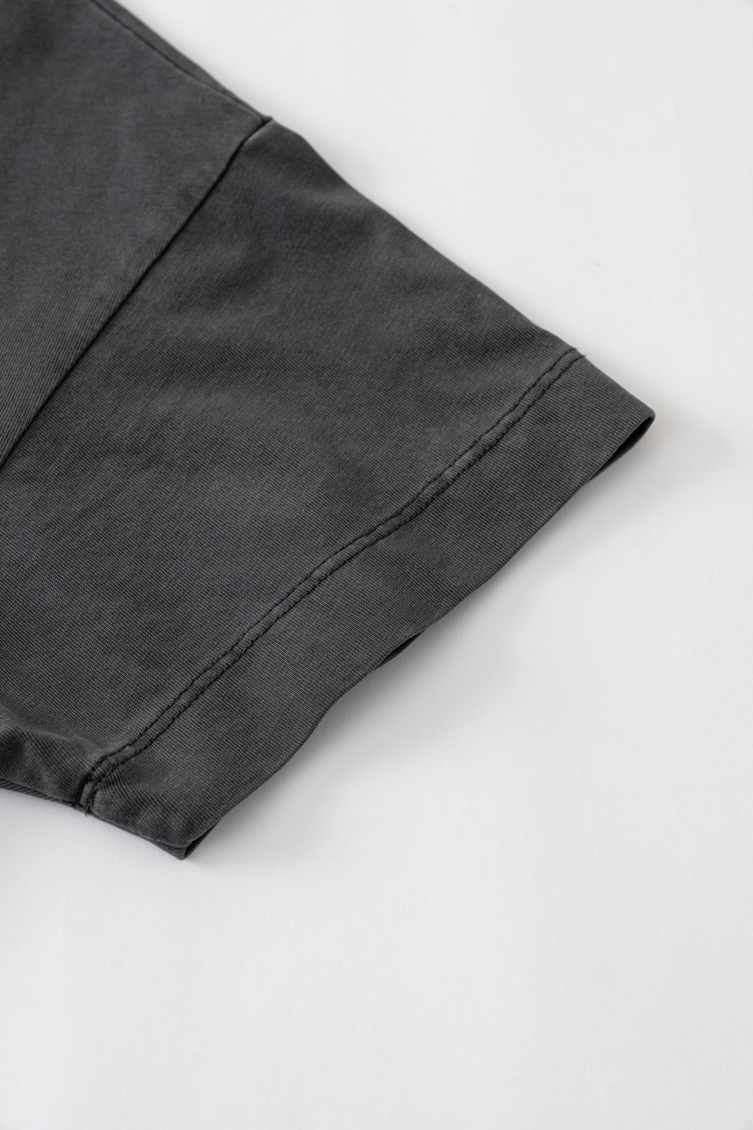 Sleeve hem stitching and textured weave close-up on Dark Gray breathable tee.
