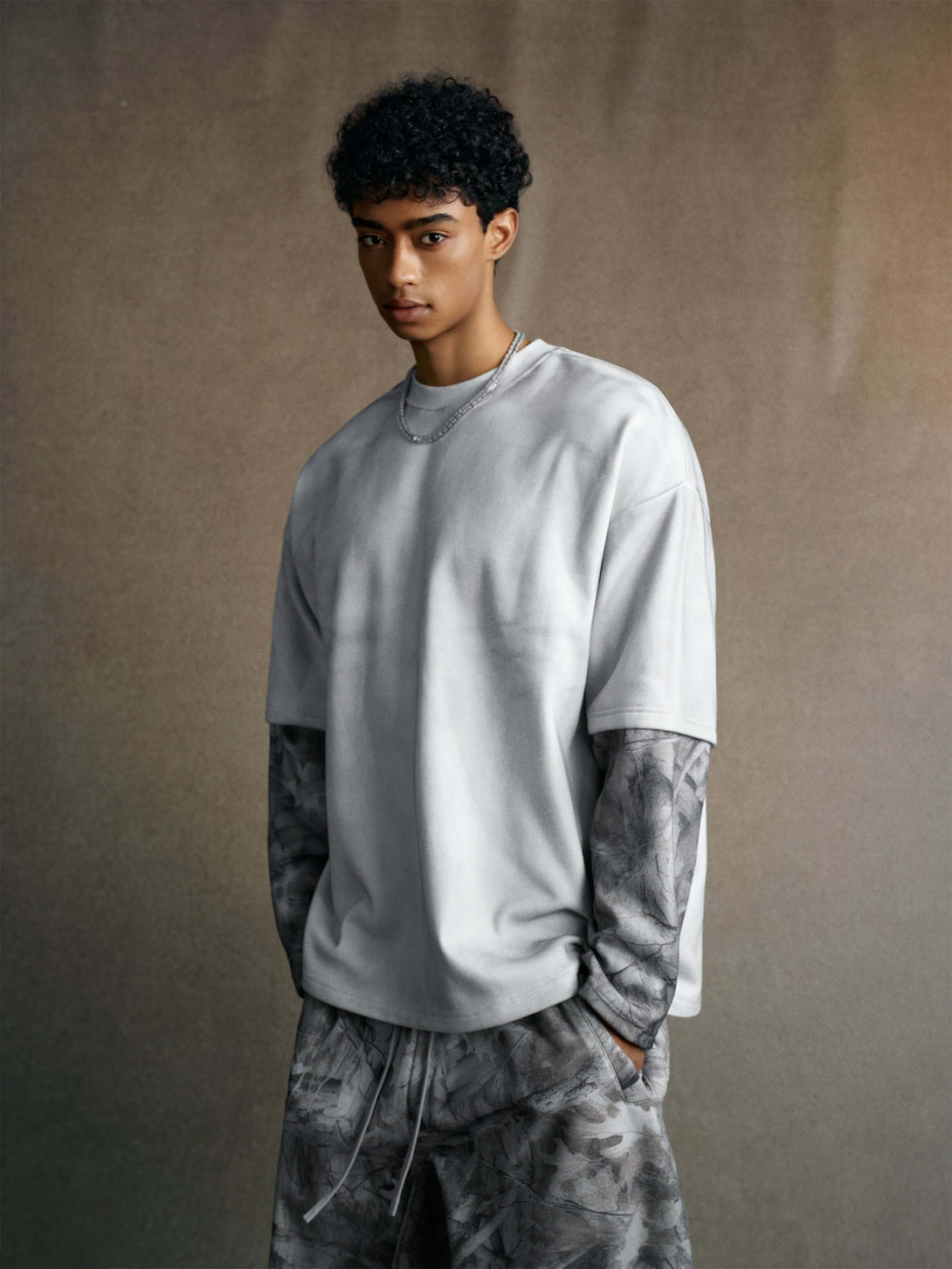 Men's 340g Gray Spray-Dye Camo Crew Neck styled with layered camo sleeves, perfect for urban fashion.