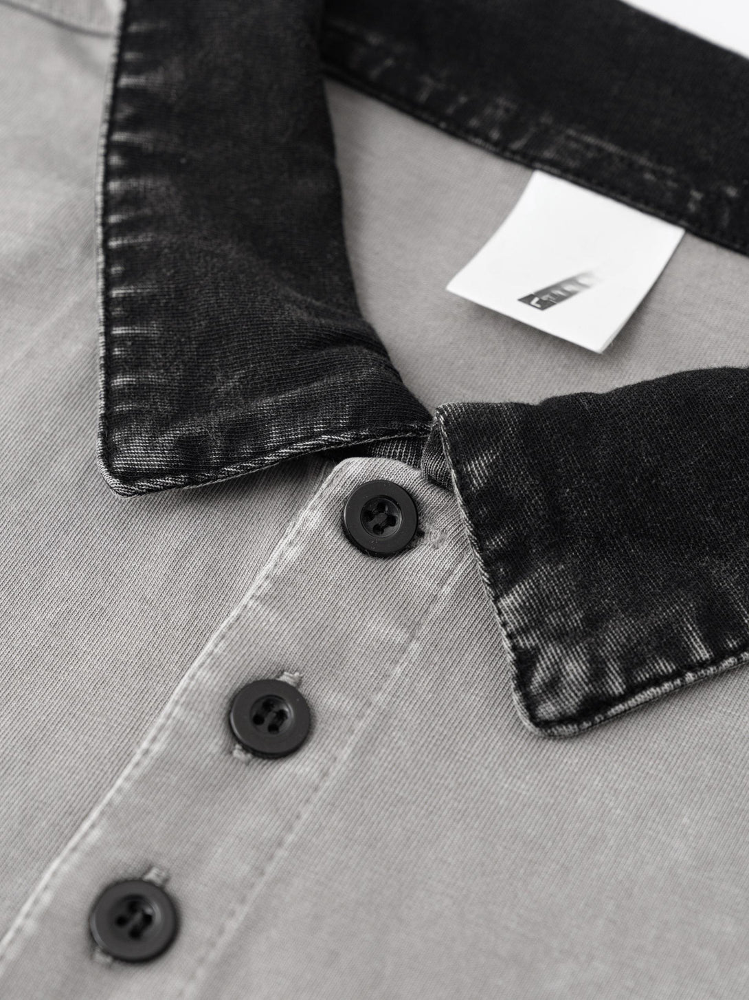 Button placket construction detail on Light Gray cotton polo, reinforced garment manufacturing technique.