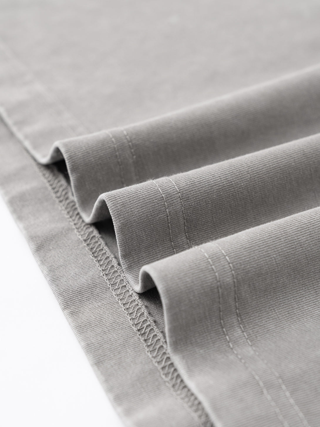 Hem finishing with vintage wash effect on Light Gray cotton polo, bulk garment production consistency.