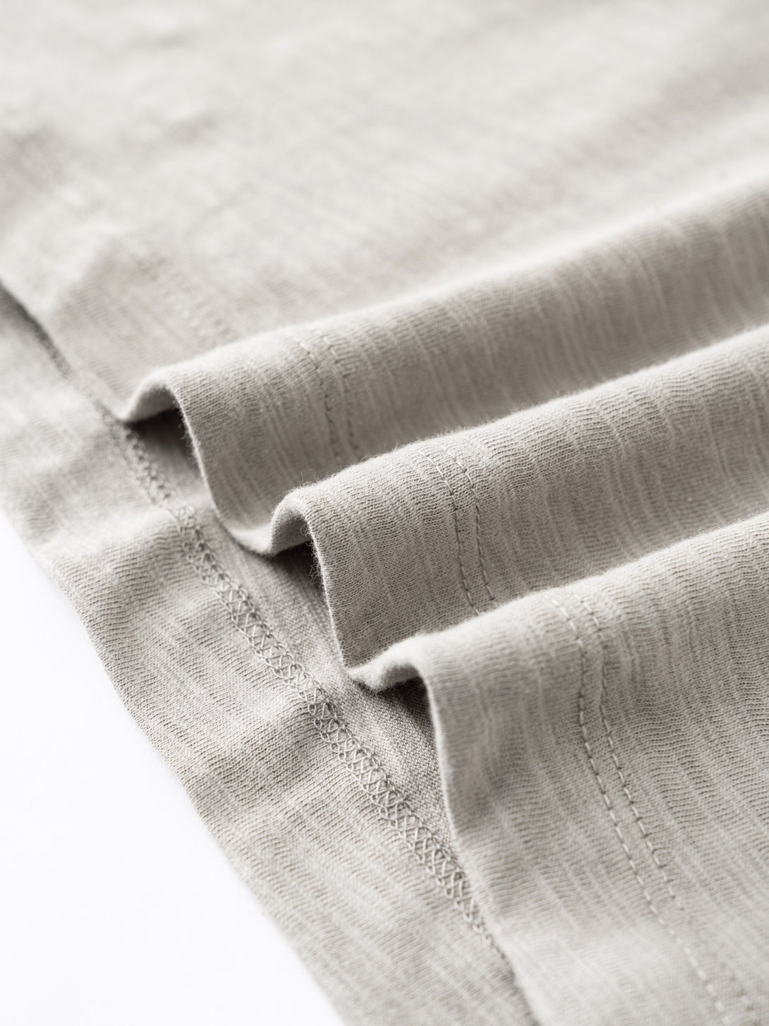 Hem finishing with yarn-dyed fabric texture on Light Gray cotton tee, breathability demonstration.
