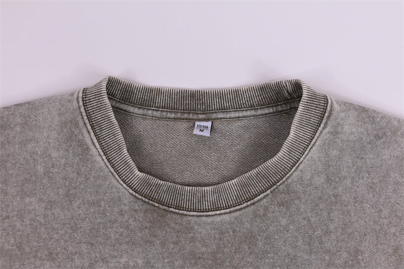 Close-up detail of front 1x1 rib collar on round-neck distressed washed vintage sweatshirt