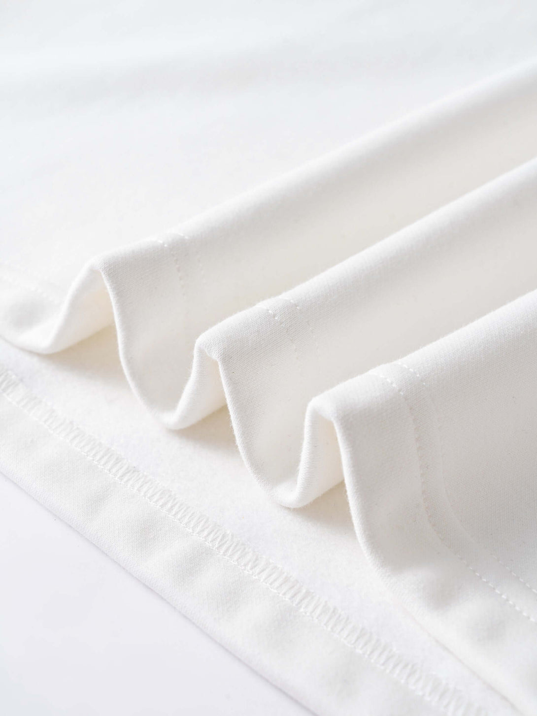 Soft white fabric close-up with layered folds, ideal for the Men's 340g White Layered Camo Sweatshirt.